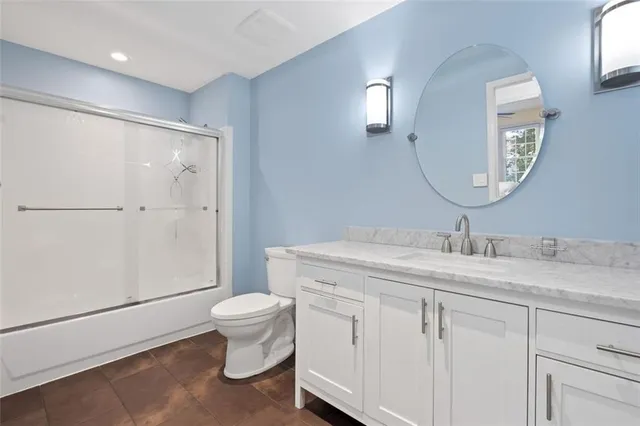 a bathroom with a granite countertop sink a toilet and a mirror
