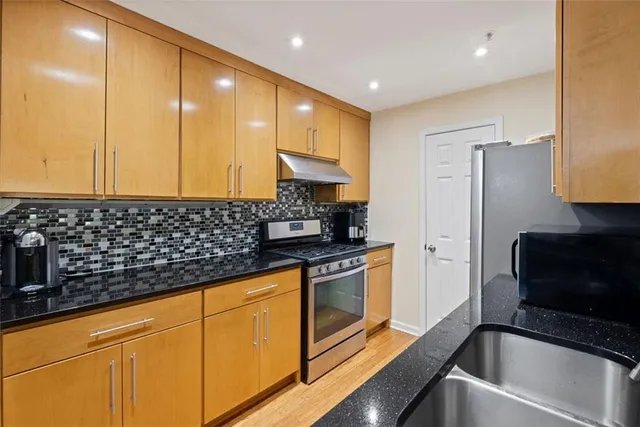 a kitchen with stainless steel appliances granite countertop a sink a stove and a refrigerator