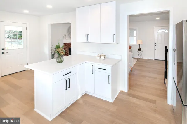 a kitchen with white cabinets appliances and wooden floor