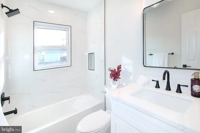 a bathroom with a bathtub sink vanity mirror and toilet