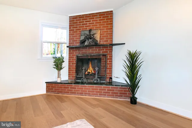 a living room with a fireplace and potted plants