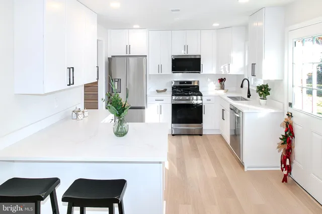 a kitchen with stainless steel appliances a white refrigerator a stove a sink a dining table and chairs