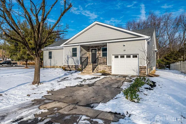 a front view of a house with a yard outdoor seating and covered with trees