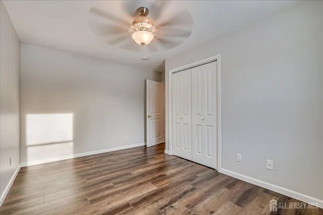 an empty room with wooden floor and ceiling fan