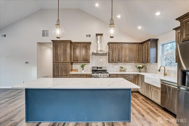 a kitchen with stainless steel appliances a sink a stove a refrigerator center island and cabinets