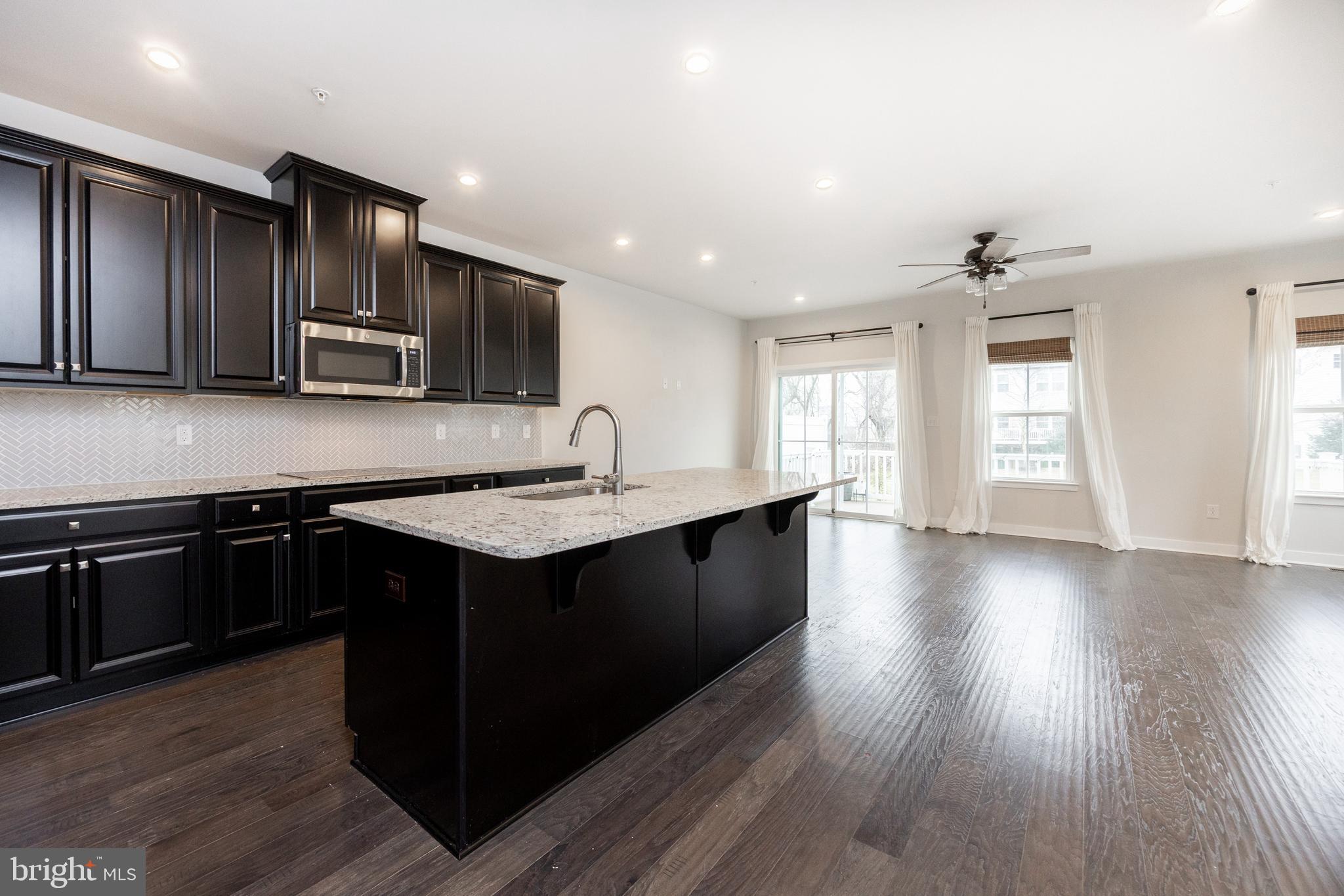 131 Mulberry Drive Malvern, PA 19355 - Photo 8 of 37 a kitchen with stainless steel appliances kitchen island granite countertop a stove a sink dishwasher and a microwave oven with wooden floor