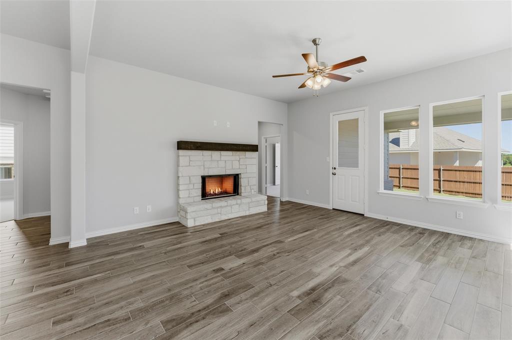 1225 Sabine River Lane Springtown, TX 76082 - Photo 10 of 25 Unfurnished living room with ceiling fan, a stone fireplace, and light wood-style flooring