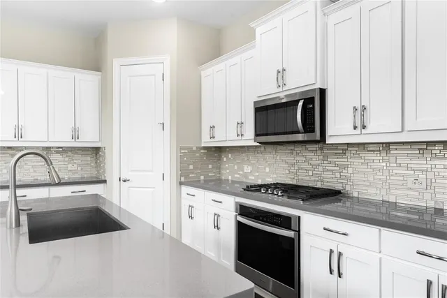a kitchen with stainless steel appliances granite countertop a sink a stove and a wooden floors