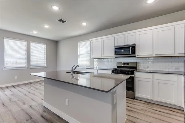 a kitchen with kitchen island white cabinets appliances and a sink