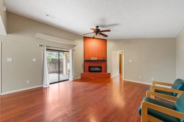 an empty room with wooden floor fireplace and windows