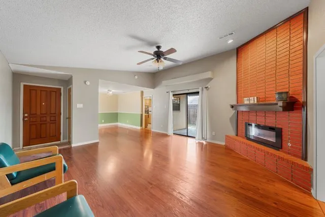 a view of an empty room with wooden floor fireplace and a window