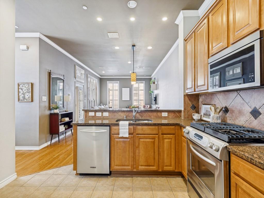 15741 Seabolt Place, Unit 28 Addison, TX 75001 - Photo 10 of 37 Kitchen with stainless steel appliances, light tile patterned floors, decorative backsplash, a peninsula, and ornamental molding