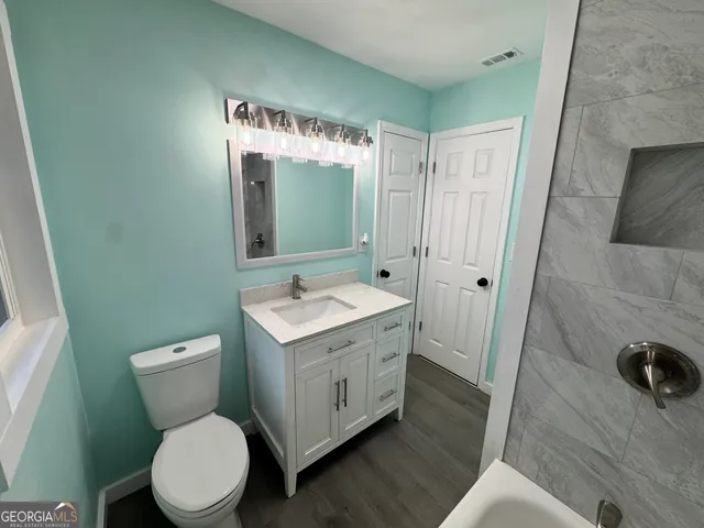 a bathroom with a granite countertop toilet sink and mirror