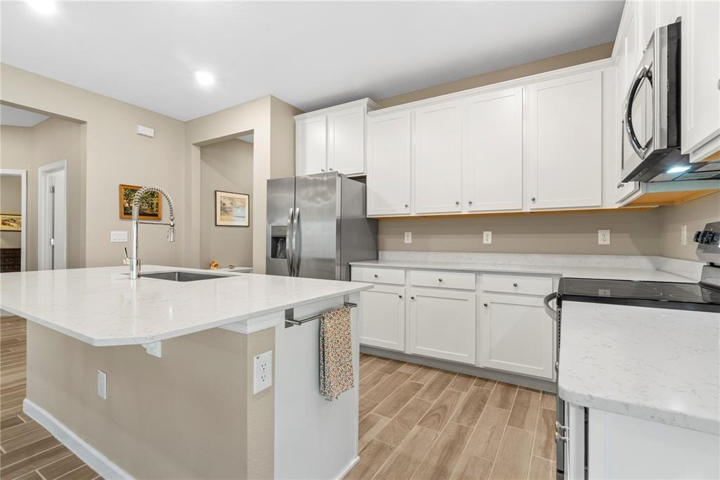 7381 Southwest 78th Terrace Ocala, FL 34474 - Photo 10 of 47 a kitchen with stainless steel appliances granite countertop a sink a stove a refrigerator and white cabinets with wooden floor