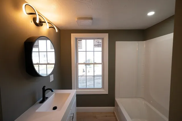 a bathroom with a tub sink and mirror