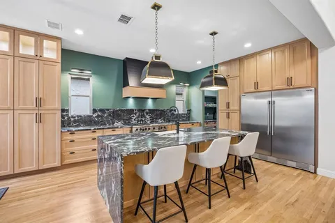 a kitchen with stainless steel appliances granite countertop a kitchen island a table and chairs in it