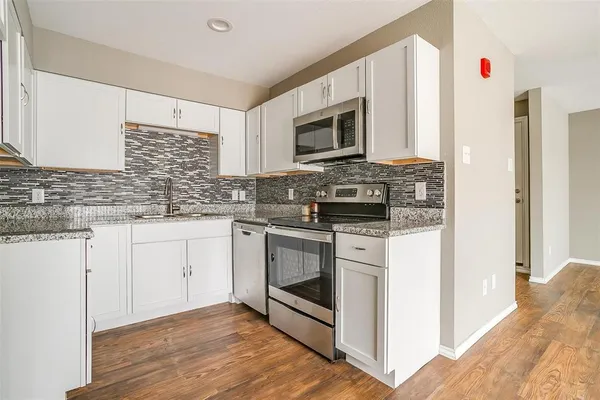 a kitchen with stainless steel appliances granite countertop a stove a sink and a microwave