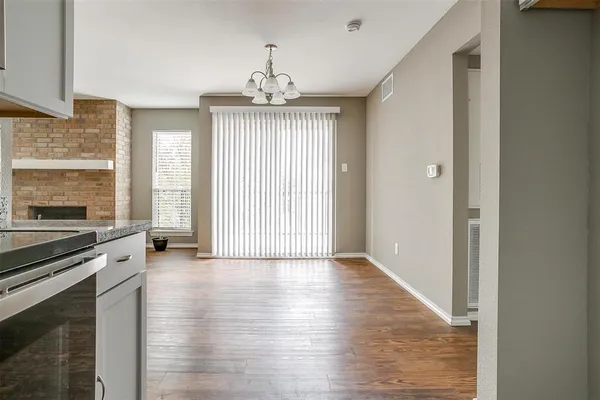 an empty room with wooden floor fireplace and windows