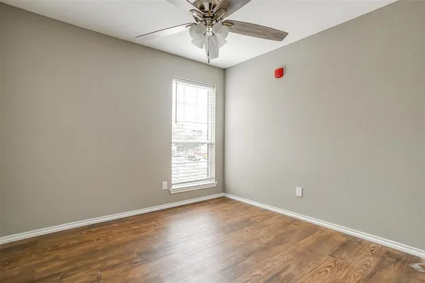an empty room with a chandelier fan and windows