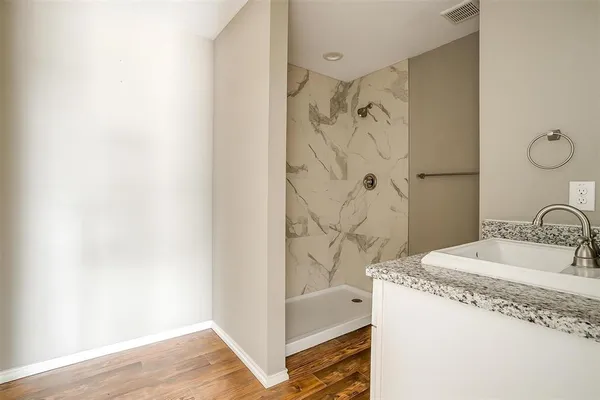 a bathroom with a granite countertop sink a mirror and shower