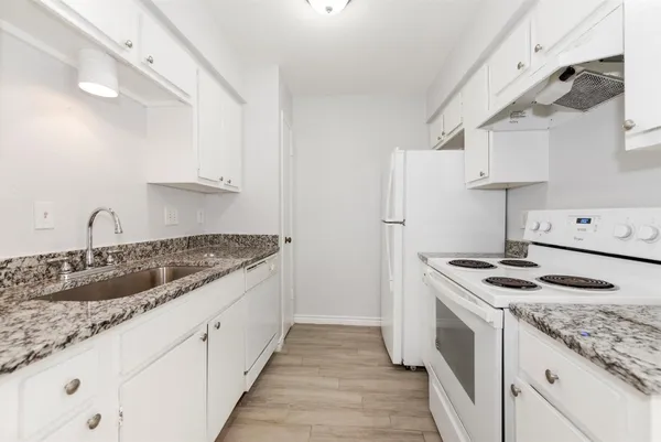 a kitchen with granite countertop a sink stove and refrigerator