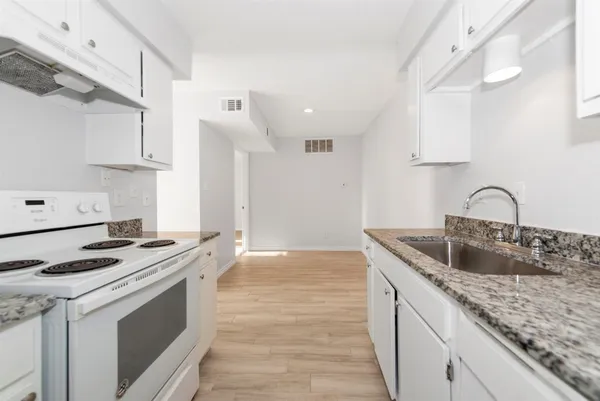 a kitchen with granite countertop a sink stove and cabinets