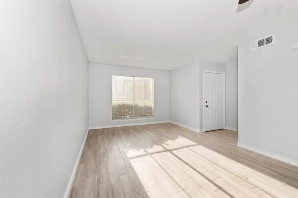 an empty room with wooden floor and windows