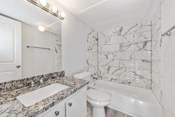 a bathroom with a granite countertop sink and a bathtub