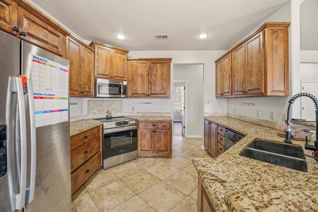 1114 Elk Ridge Drive Stephenville, TX 76401 - Photo 12 of 32 a kitchen with a sink stove and refrigerator