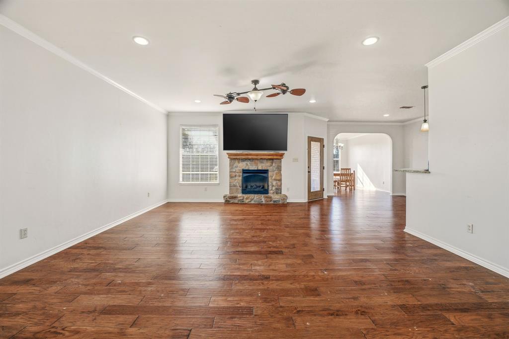 1114 Elk Ridge Drive Stephenville, TX 76401 - Photo 6 of 32 an empty room with wooden floor and fireplace