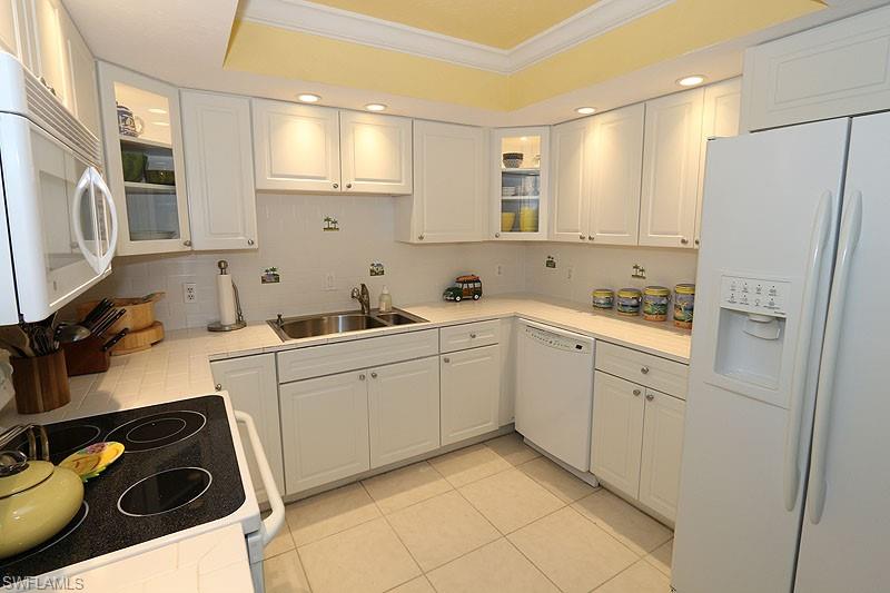 341 3rd Avenue South, Unit 341 Naples, FL 34102 - Photo 11 of 18 a kitchen with a sink a refrigerator and cabinets