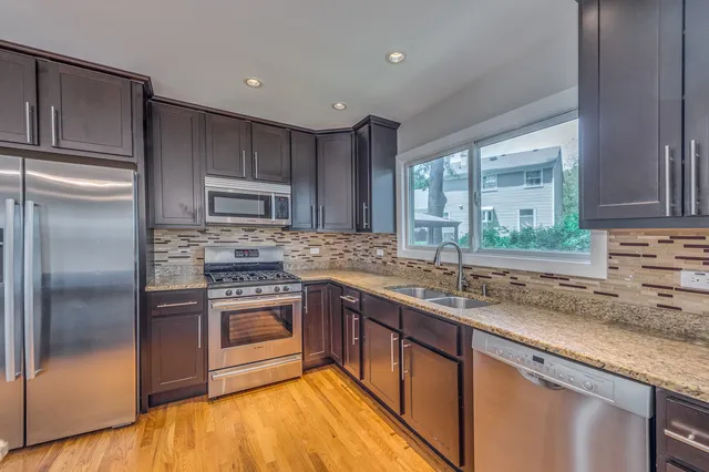 a kitchen with stainless steel appliances granite countertop a sink stove and refrigerator