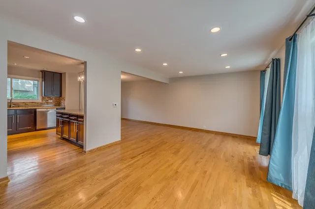 a view of a kitchen with kitchen island wooden floor and stainless steel appliances