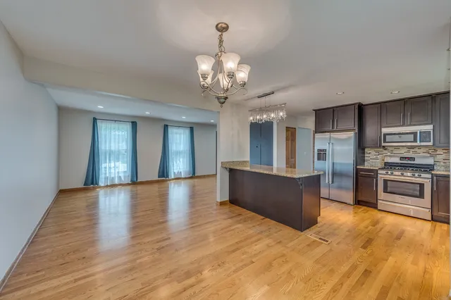 a large kitchen with stainless steel appliances granite countertop a oven and a wooden floors