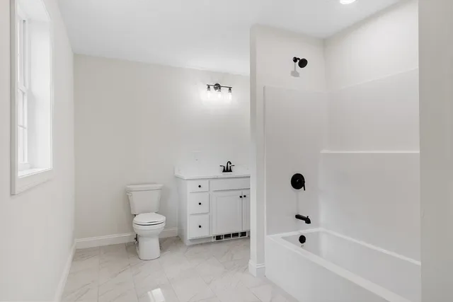 a bathroom with a toilet a sink a mirror and bathtub