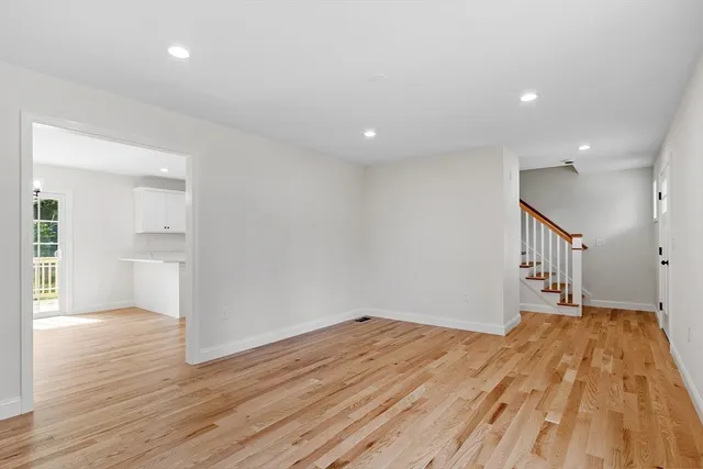 a big room with wooden floor and a kitchen