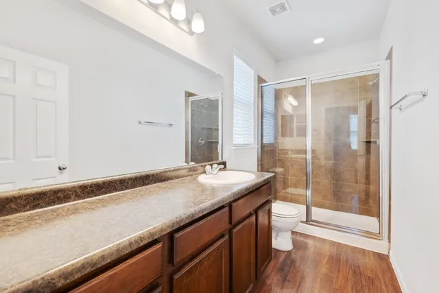 a bathroom with a granite countertop sink a toilet a mirror and shower