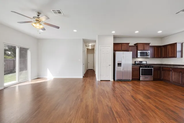 a view of kitchen with cabinets wooden floor and stainless steel appliances
