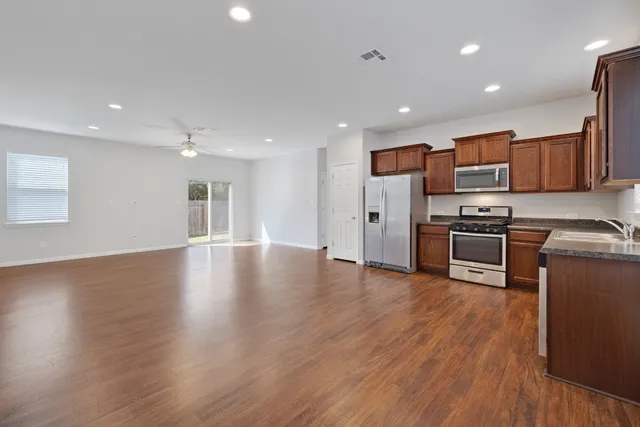 a kitchen with stainless steel appliances granite countertop a stove top oven a sink with wooden floors and cabinets