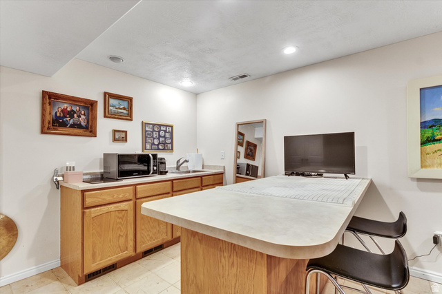 2863 Fallentine Road Sandy, UT 84093 - Photo 38 of 48 Kitchenette featuring light wood-finish cabinetry, a single basin sink, and a contrasting countertop with an extended breakfast bar