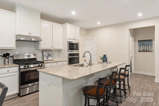 a kitchen with stainless steel appliances granite countertop a white cabinets and wooden floor