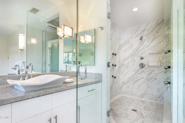 a bathroom with a granite countertop sink a mirror a vanity and shower
