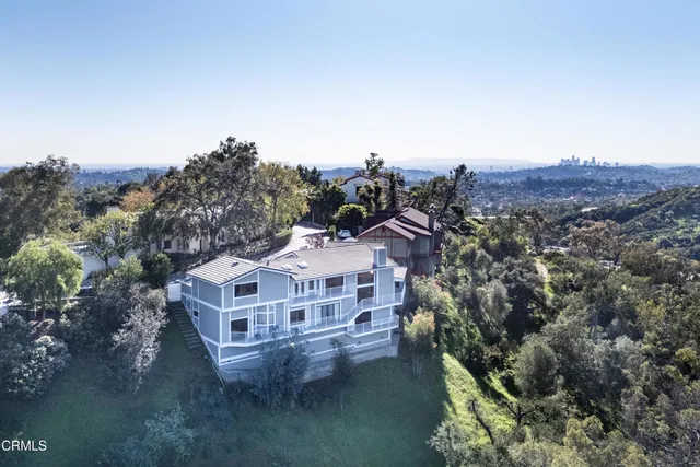 an aerial view of residential houses with outdoor space and trees