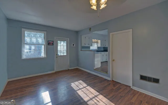 a view of an empty room with window and wooden floor