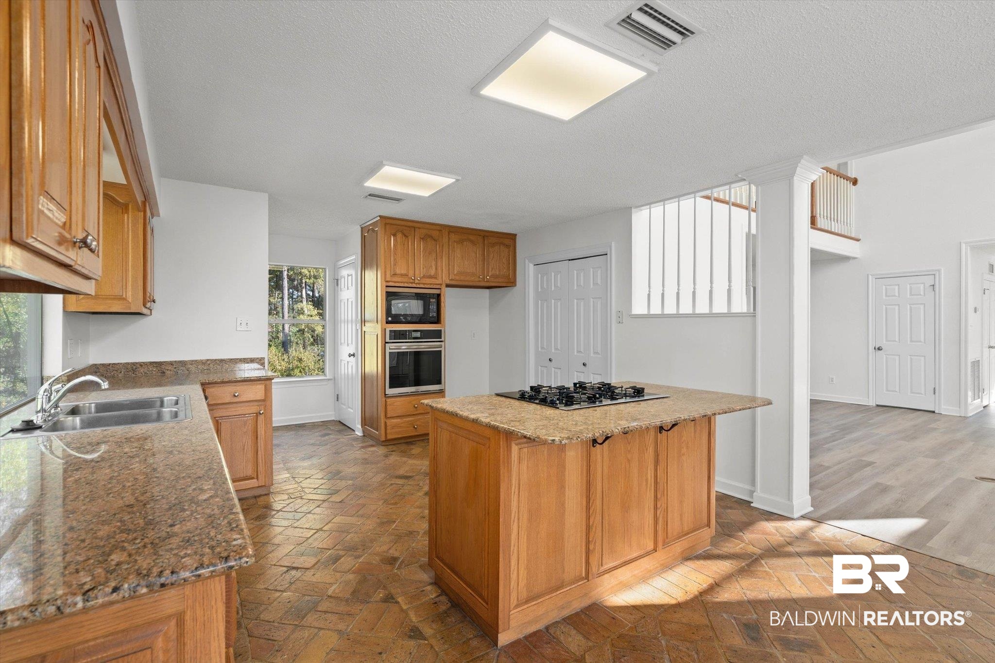 3847 Riviere Du Chien Road Mobile, AL 36693 - Photo 15 of 51 Kitchen featuring black appliances, light stone counters, a kitchen island, wood finish cabinetry, and brick flooring