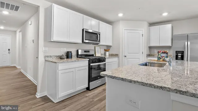 a kitchen with granite countertop white cabinets and stainless steel appliances