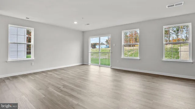 a view of an empty room with wooden floor and windows
