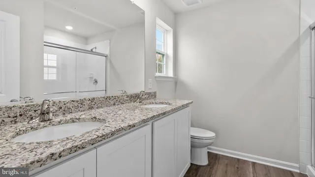 a bathroom with a granite countertop sink a toilet and a mirror