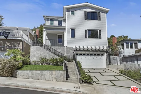 a front view of house with yard and trees in the background