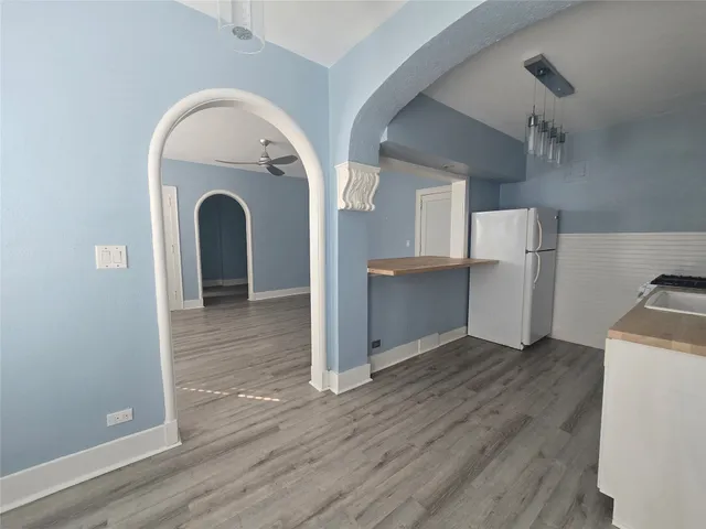a view of a kitchen with refrigerator and wooden floor